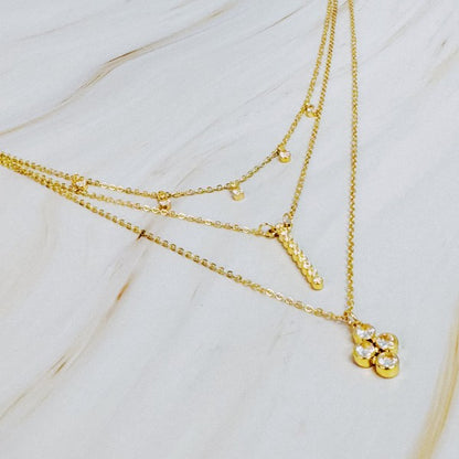 Detailed view of layered gold necklace with bezel crystals arranged neatly on marble.