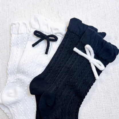 Flat lay of black and white Yarn Bow Socks set with contrasting yarn bows.