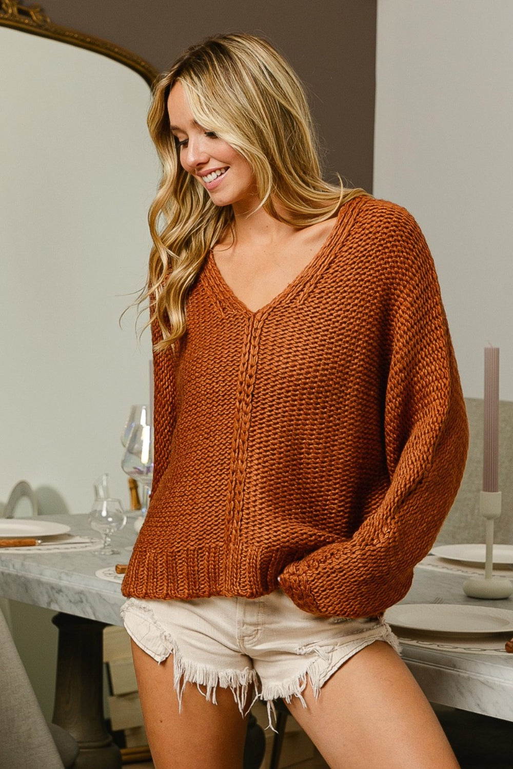 Cinnamon colored cable-knit sweater with long sleeves and a V-neck neckline.