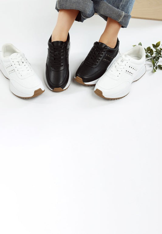 Model wearing black Athion Studded Leather Sneakers while holding white pair