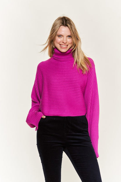 Front view Giada Plus Size Mock Neck Wide Sleeves Sweater in fuchsia with black slacks.