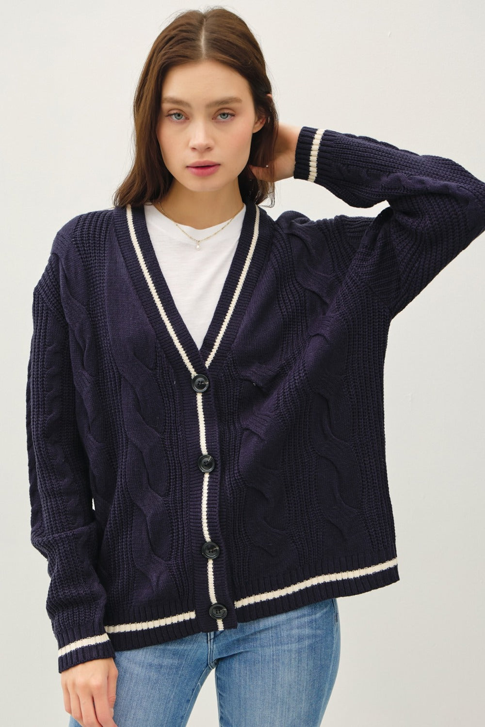 Navy and white contrast trim cable-knit cardigan with woven details and button closure.