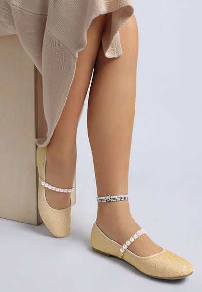 Second side view of woman wearing gold Corphee Pearl Strapped Glitter Ballerinas showing flexible sole and strap.