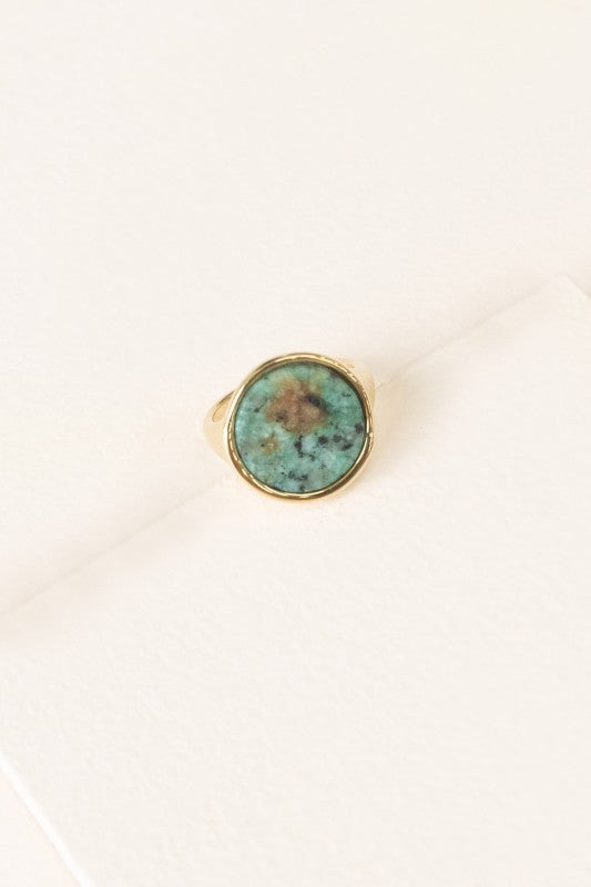 Top view of Ambition Stone Ring in Pine with round green stone in gold setting.