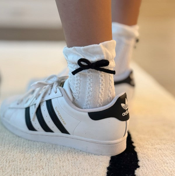 Model wearing white Yarn Bow Socks styled with sneakers and playful bow detail.