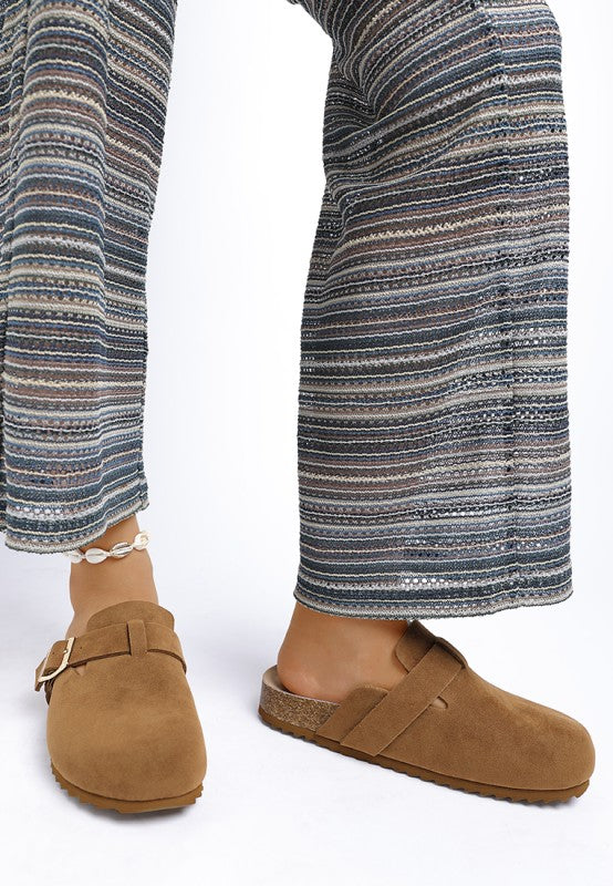 Model wearing Tan Ratiha Mules showing front and medial side view in faux suede finish.