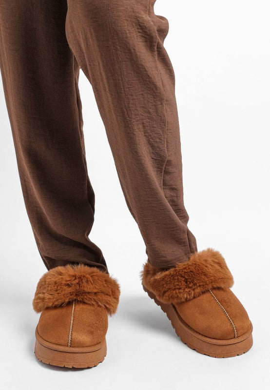Model wearing Tan Portho Faux Fur Slip Ons paired with joggers for chic lounge style.
