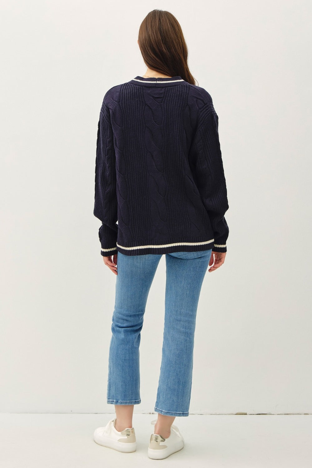 Navy and white contrast trim cable-knit cardigan with woven details and button closure.