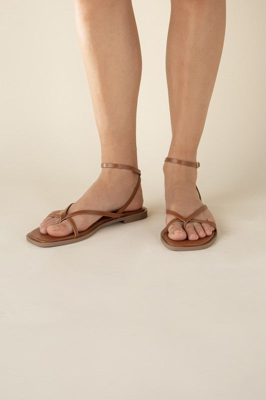 Tan stylish strappy flat sandals with an open toe and square shape.