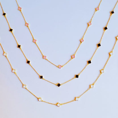 Photo of the black, cream and pink options of the Petite Colored Clover Necklace with gold clover charm.