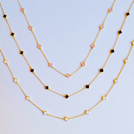 Photo of the black, cream and pink options of the Petite Colored Clover Necklace with gold clover charm.