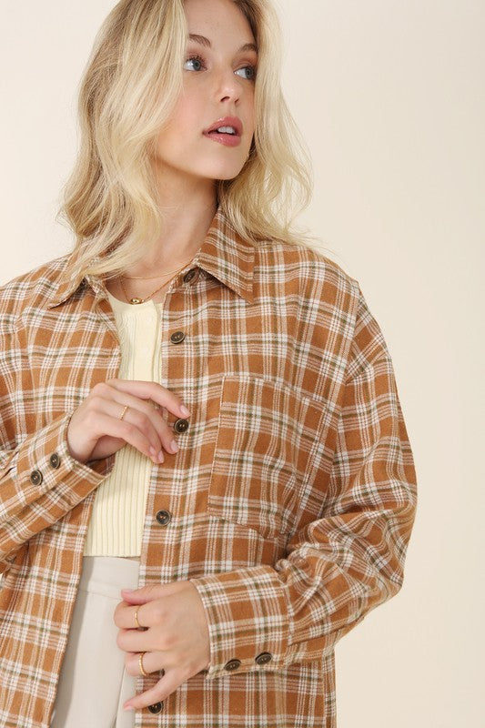 A button-front plaid shirt in rich fall colors, featuring a collared neckline, long sleeves with drop shoulders, and a chest pocket. 