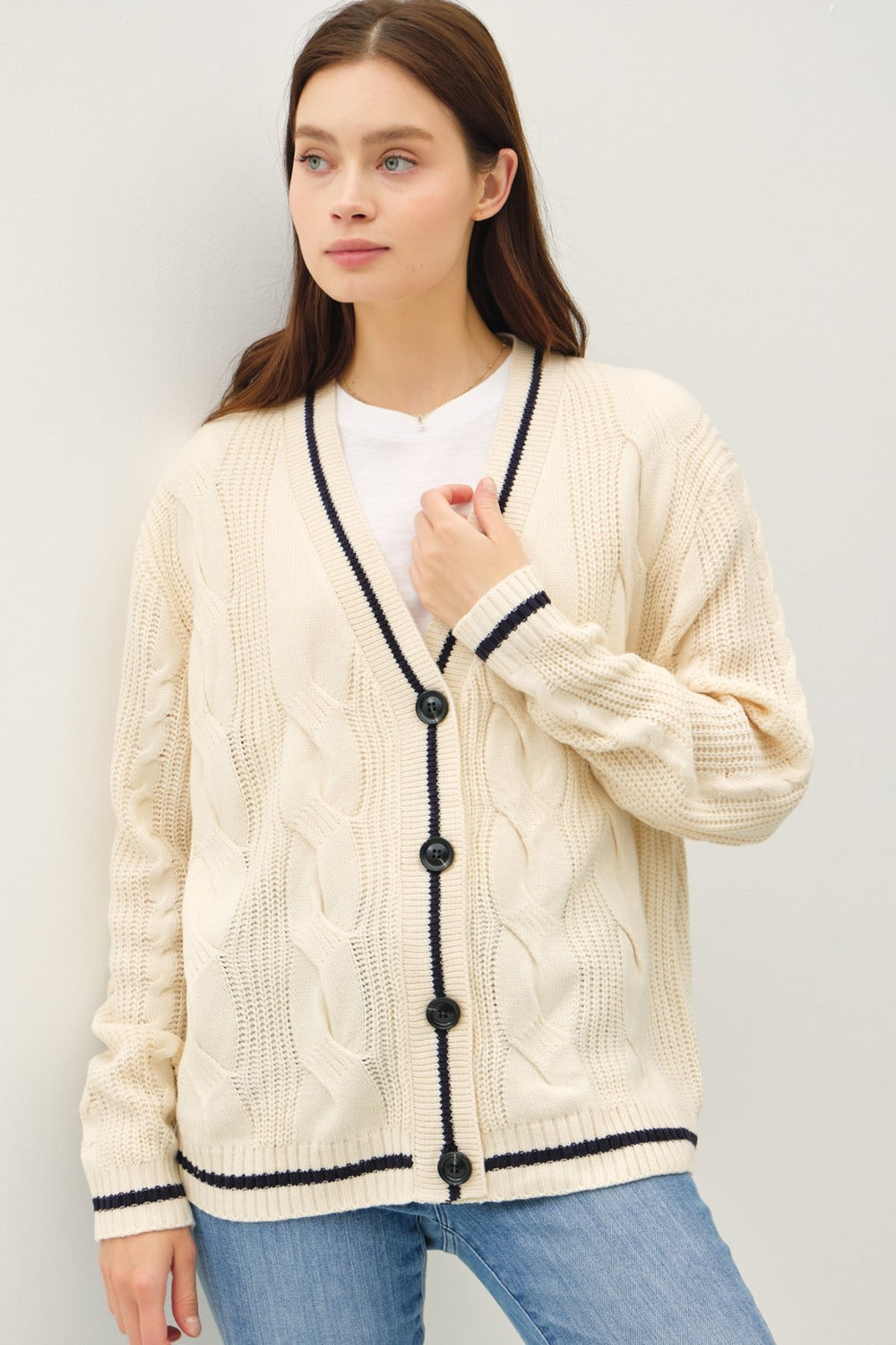 Natural and black contrast trim cable-knit cardigan with woven details and button closure.