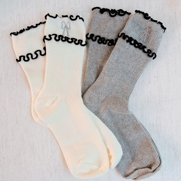 Flat lay of cream and grey Ribbon Ripple Socks with ripple trim and ribbon embroidery.