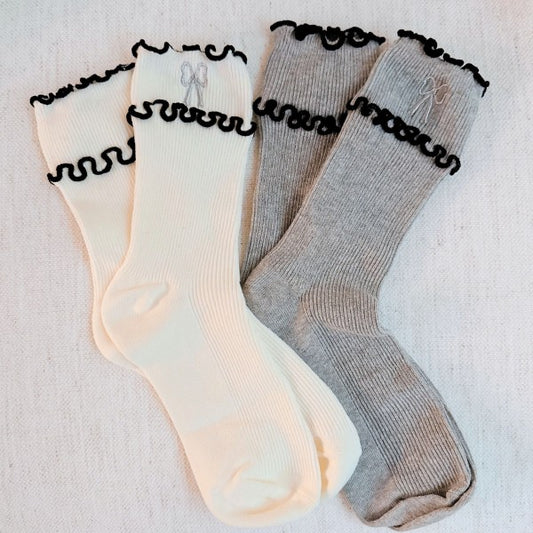 Flat lay of cream and grey Ribbon Ripple Socks with ripple trim and ribbon embroidery.