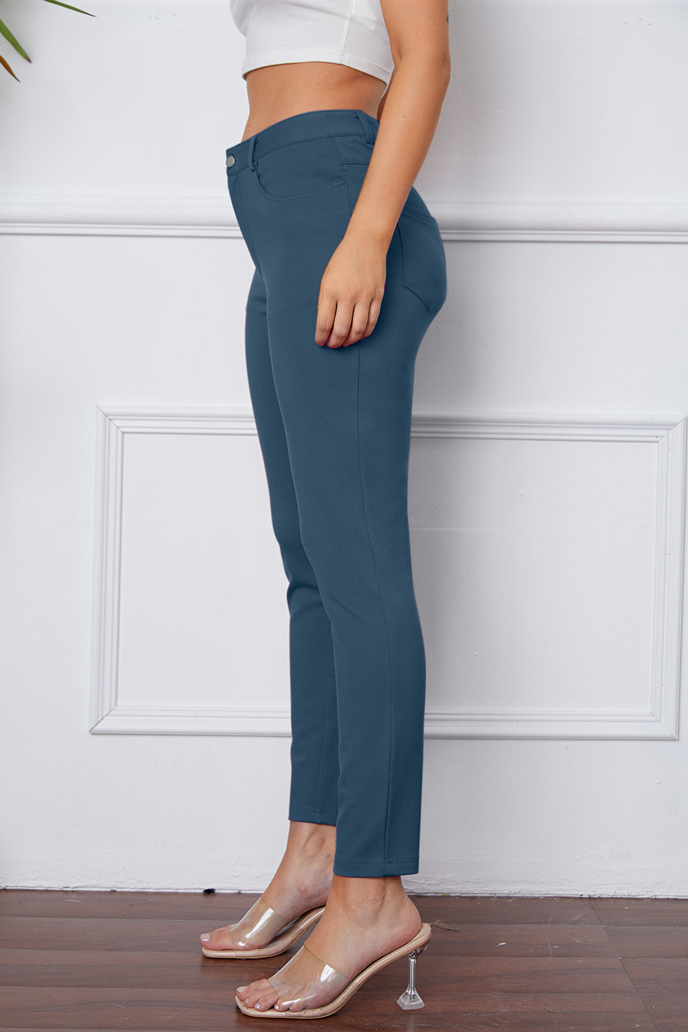 Dusty blue stretchy high-waisted pants feature pockets, a zip fly, and belt loops. 