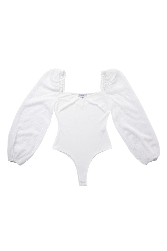 White bodysuit with long puff sleeves and Swiss dot mesh. Features a sweetheart neckline and snap button closure at the bottom