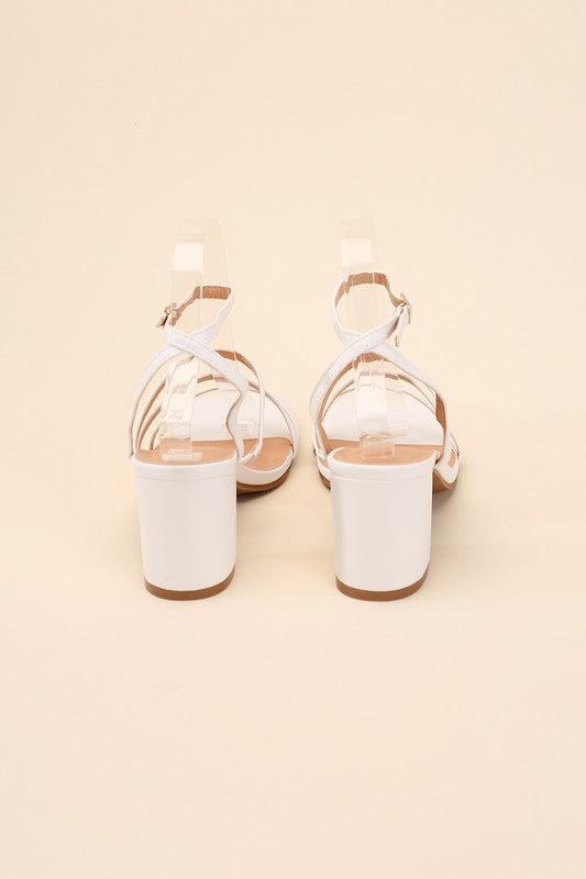 White strappy sandals with a 2" low heel, ankle strap closure, and criss-cross embellishments.