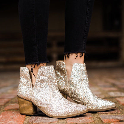 Model wearing Fiera glitter booties with 3-inch heel, perfect for holiday looks.
