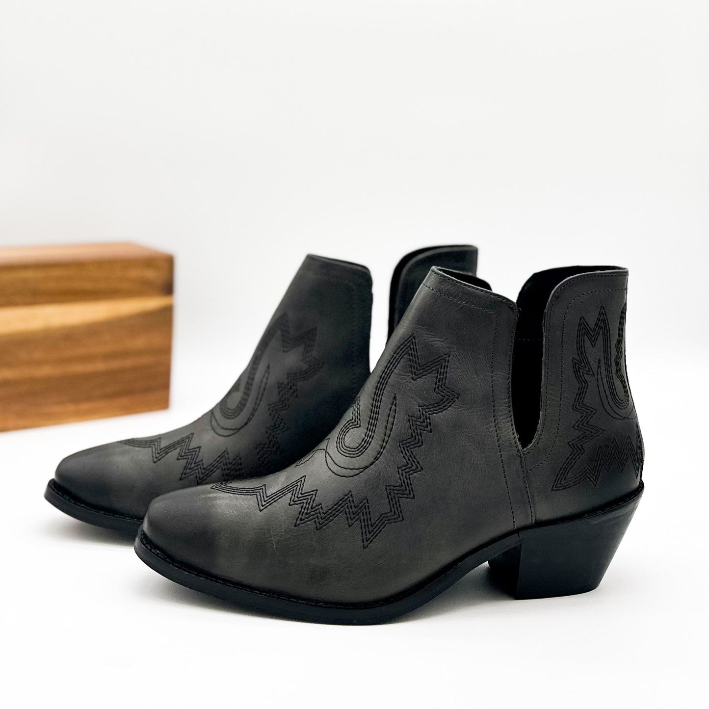 Black leather booties with Western embroidery, roomy snip toe, cushioned footbed, and ankle slits.