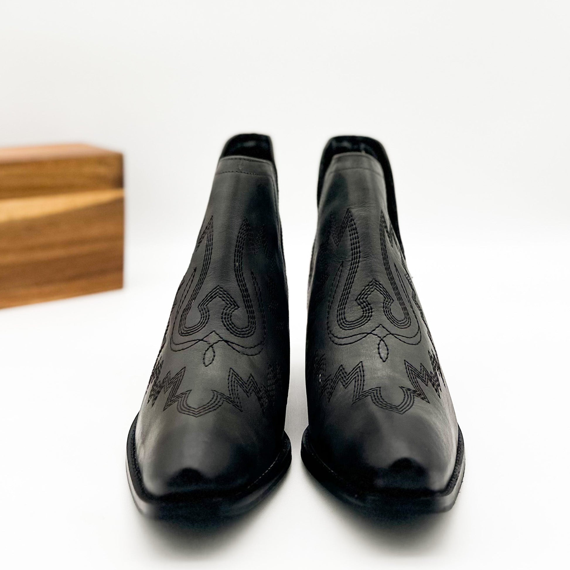 Black leather booties with Western embroidery, roomy snip toe, cushioned footbed, and ankle slits.