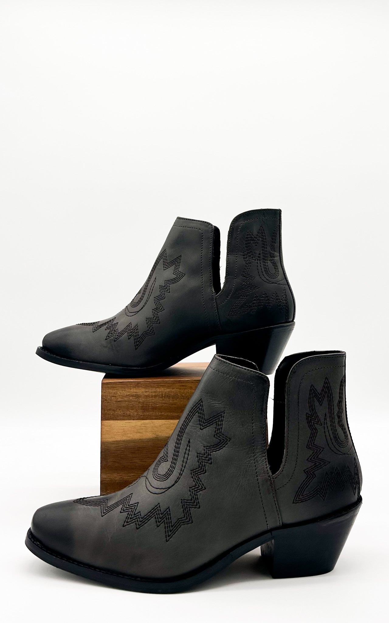 Black leather booties with Western embroidery, roomy snip toe, cushioned footbed, and ankle slits.