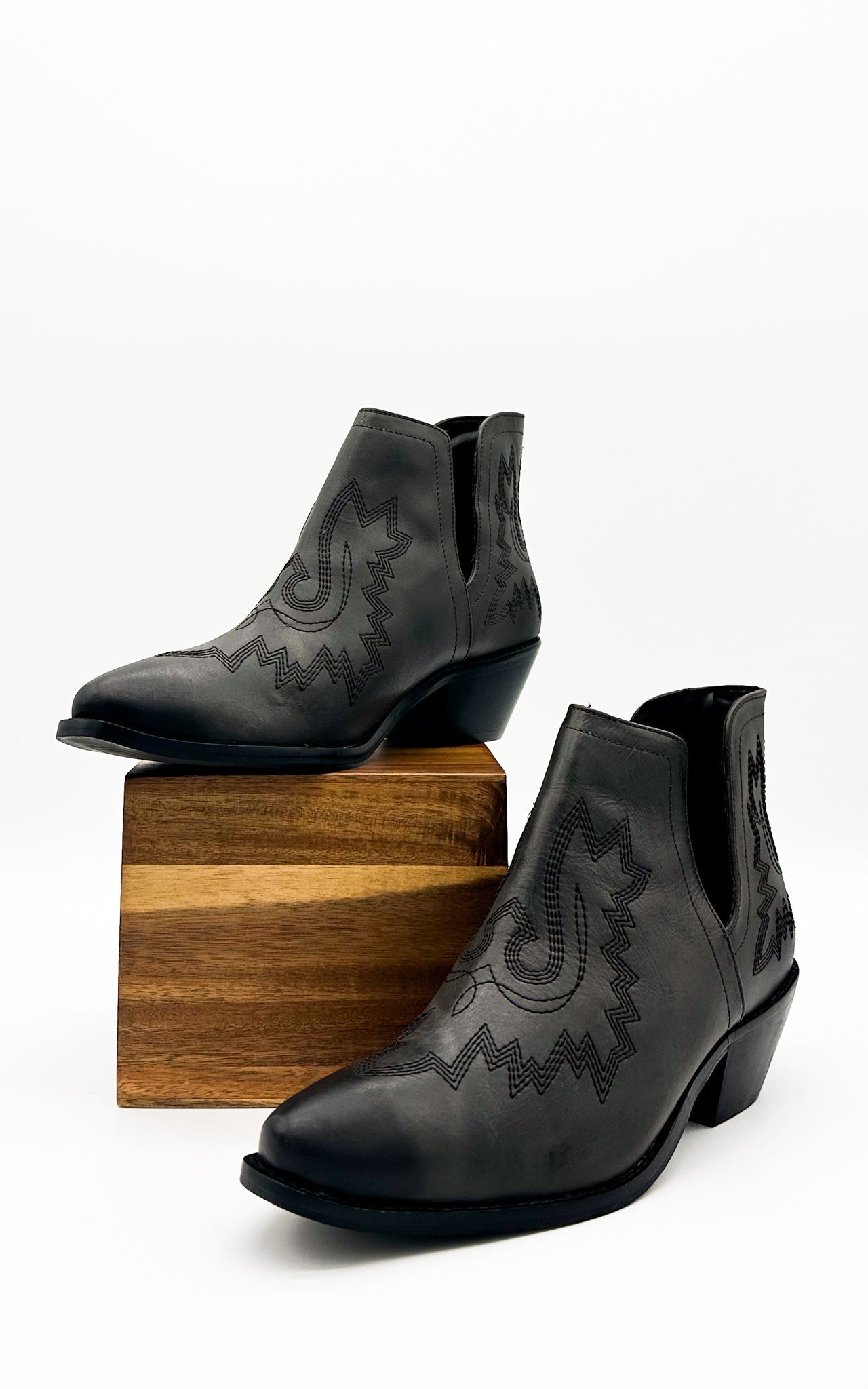 Black leather booties with Western embroidery, roomy snip toe, cushioned footbed, and ankle slits.