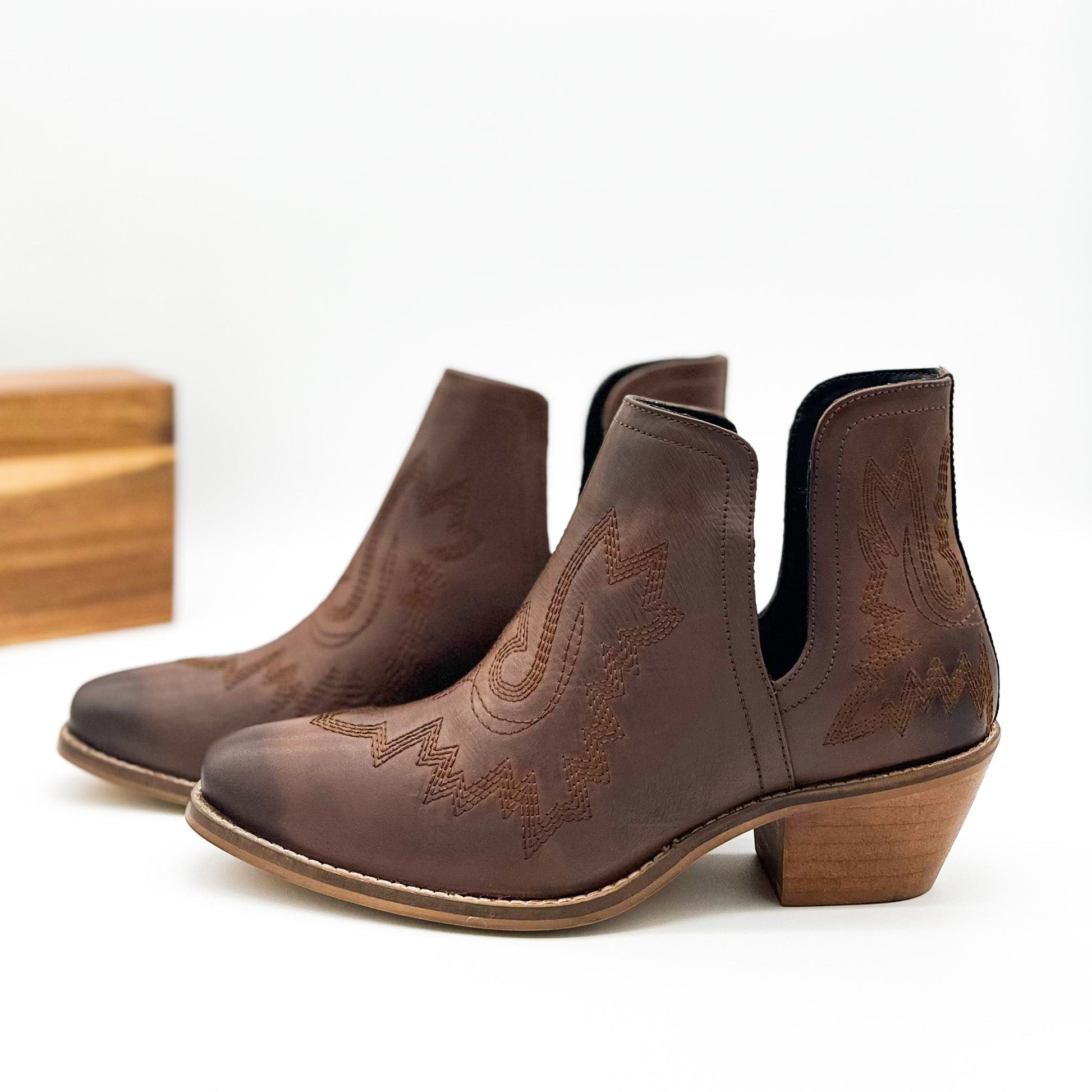 Brown leather booties with Western embroidery, roomy snip toe, cushioned footbed, and ankle slits.