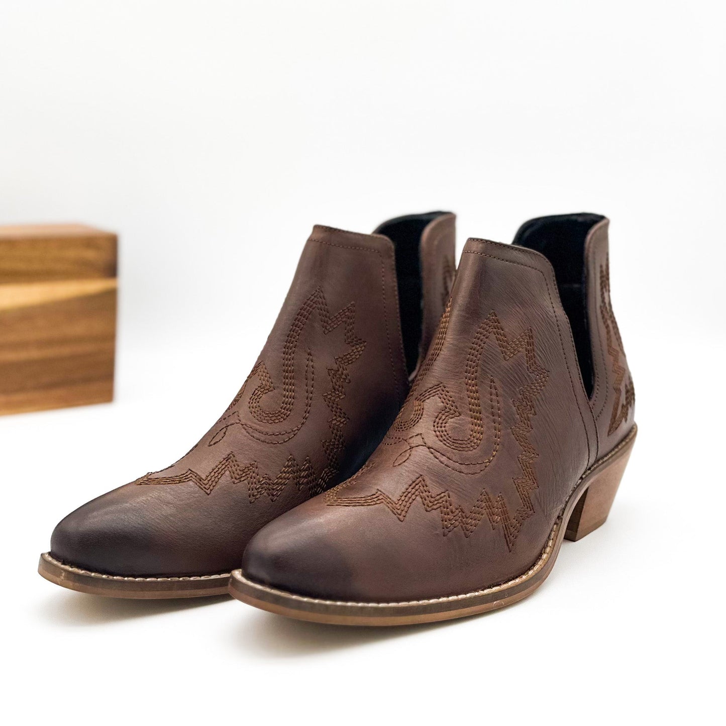 Brown leather booties with Western embroidery, roomy snip toe, cushioned footbed, and ankle slits.