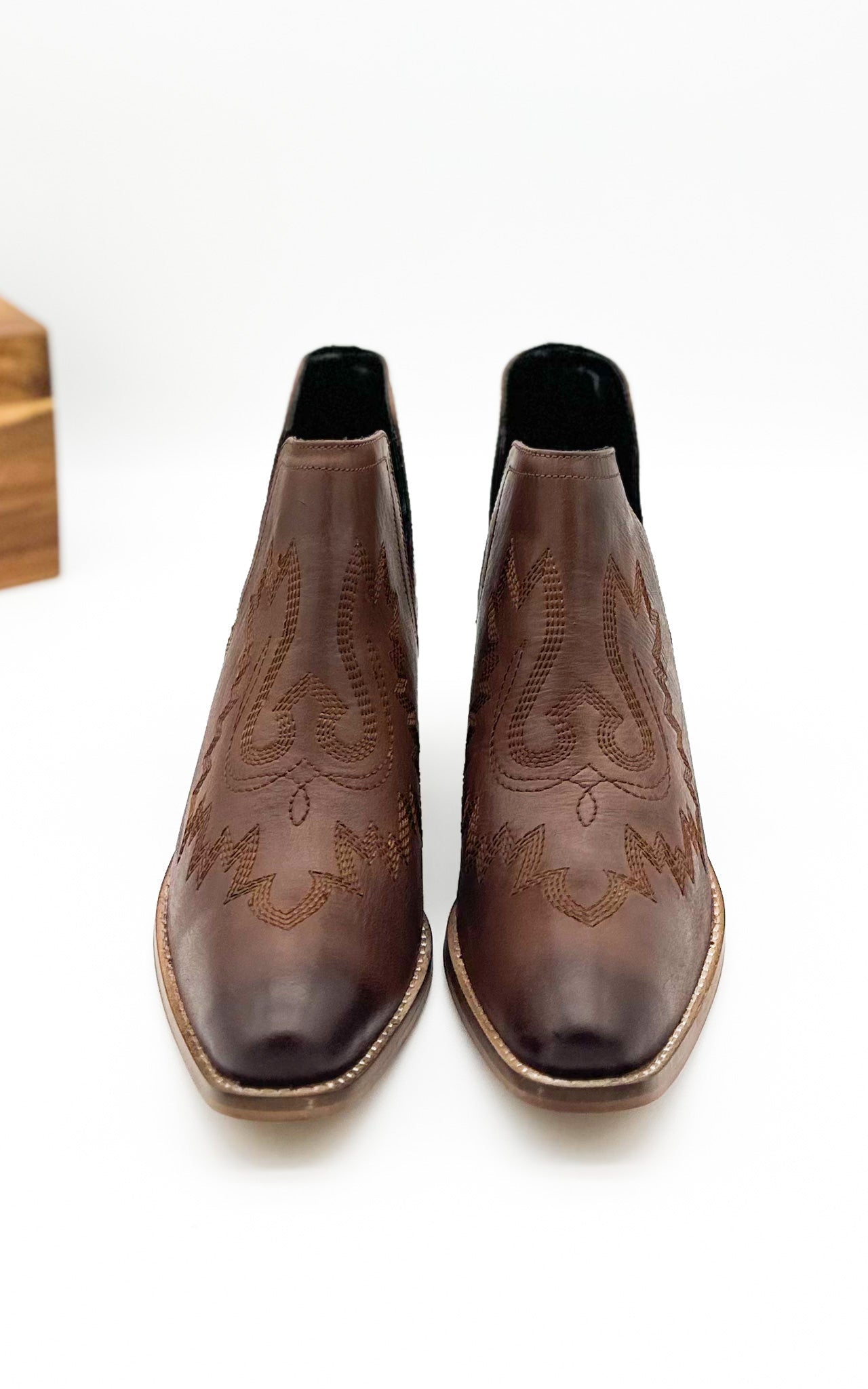 Brown leather booties with Western embroidery, roomy snip toe, cushioned footbed, and ankle slits.