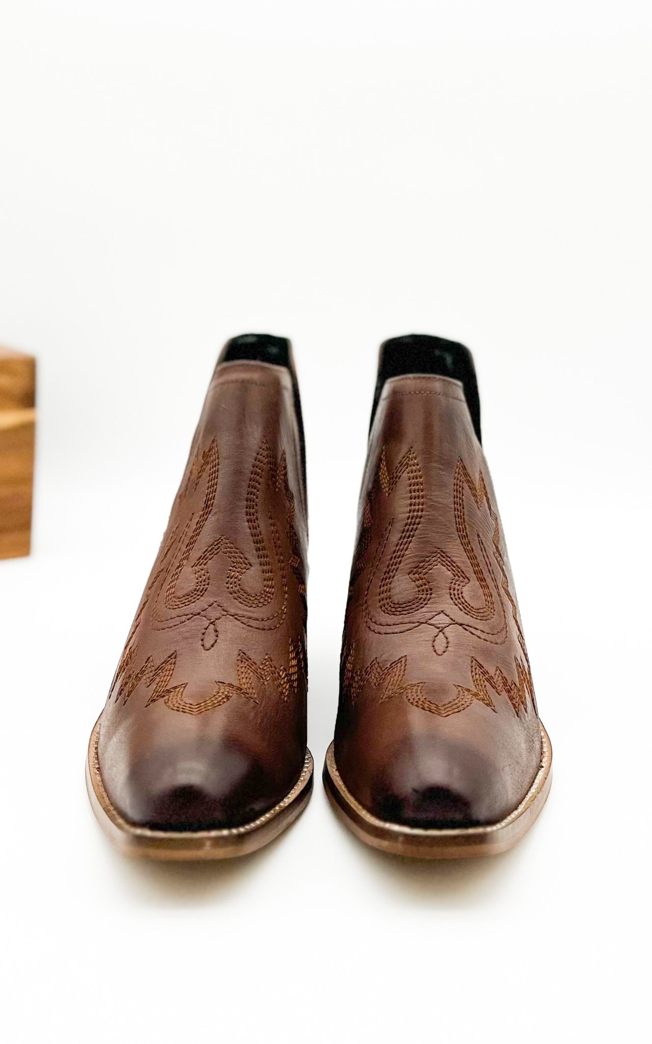 Brown leather booties with Western embroidery, roomy snip toe, cushioned footbed, and ankle slits.