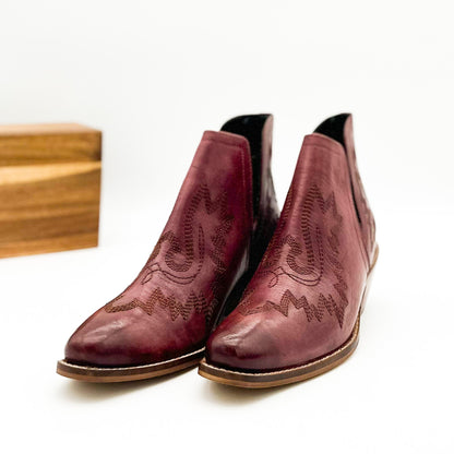 Burgandy leather booties with Western embroidery, roomy snip toe, cushioned footbed, and ankle slits.