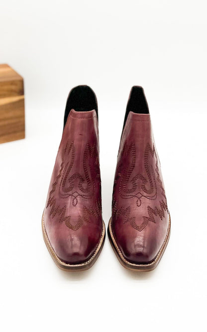 Burgandy leather booties with Western embroidery, roomy snip toe, cushioned footbed, and ankle slits.