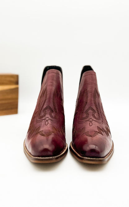 Burgandy leather booties with Western embroidery, roomy snip toe, cushioned footbed, and ankle slits.