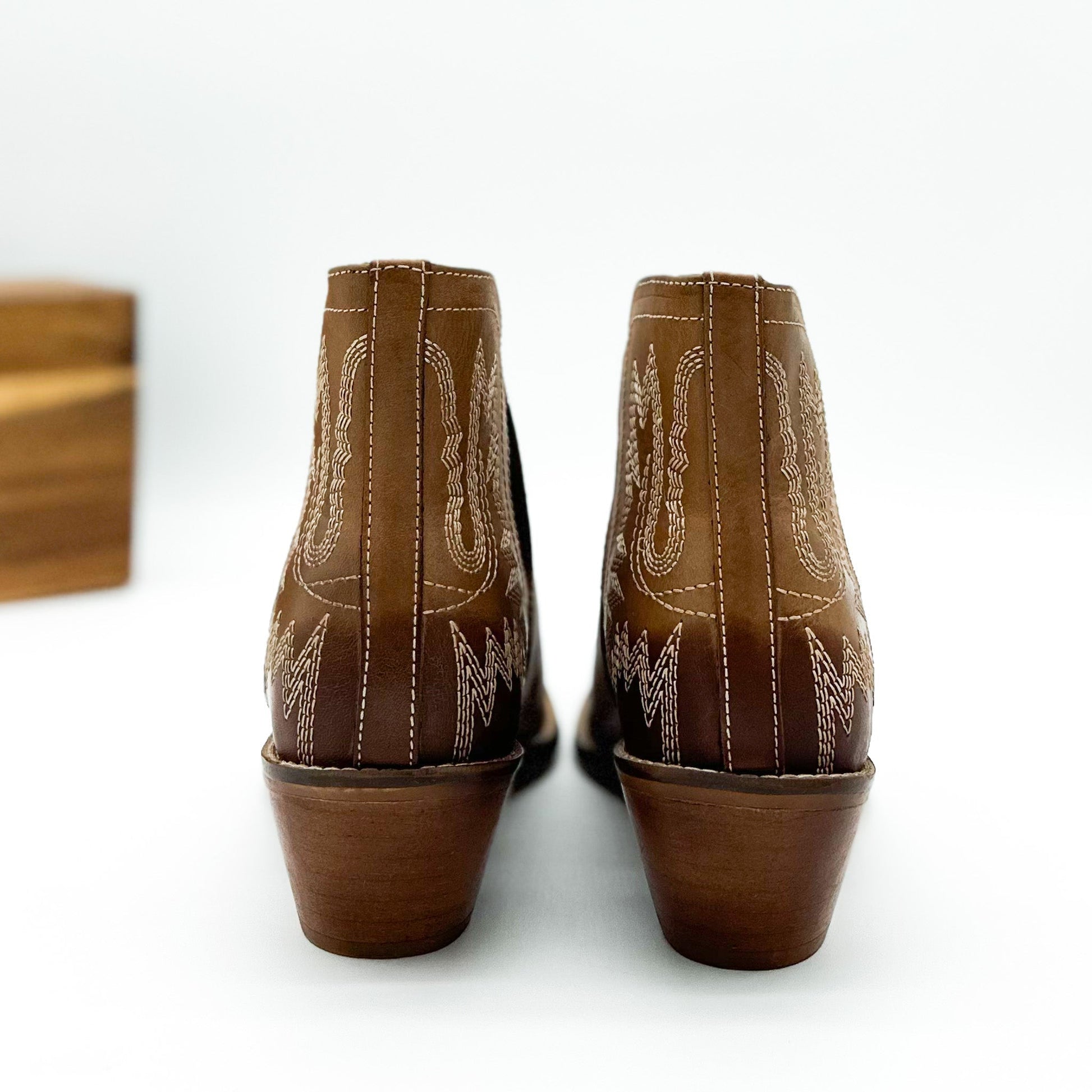 Tan leather booties with Western embroidery, roomy snip toe, cushioned footbed, and ankle slits.