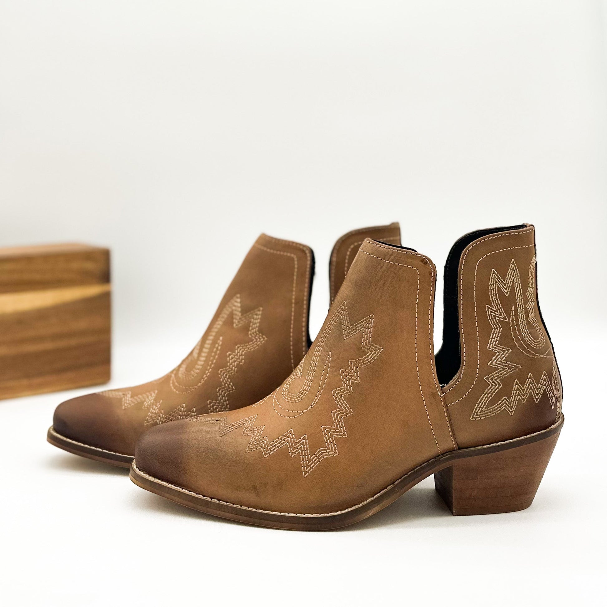 Tan leather booties with Western embroidery, roomy snip toe, cushioned footbed, and ankle slits.