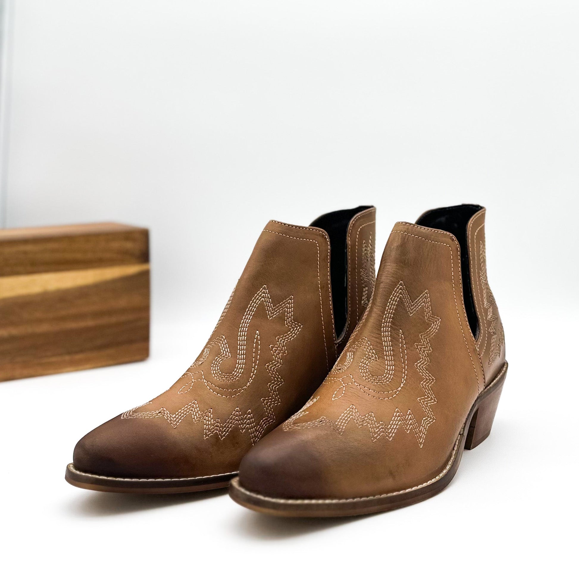 Tan leather booties with Western embroidery, roomy snip toe, cushioned footbed, and ankle slits.