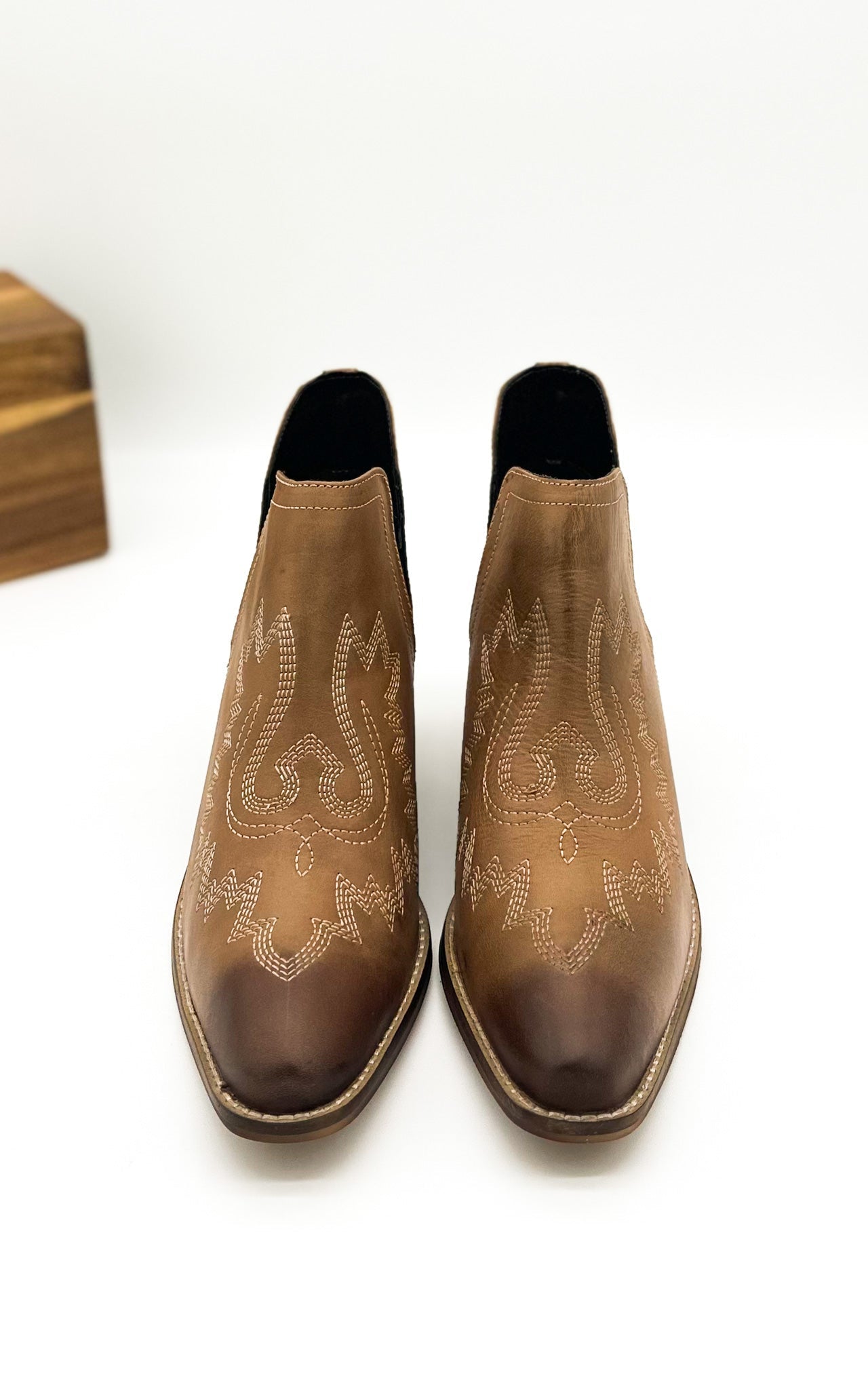 Tan leather booties with Western embroidery, roomy snip toe, cushioned footbed, and ankle slits.