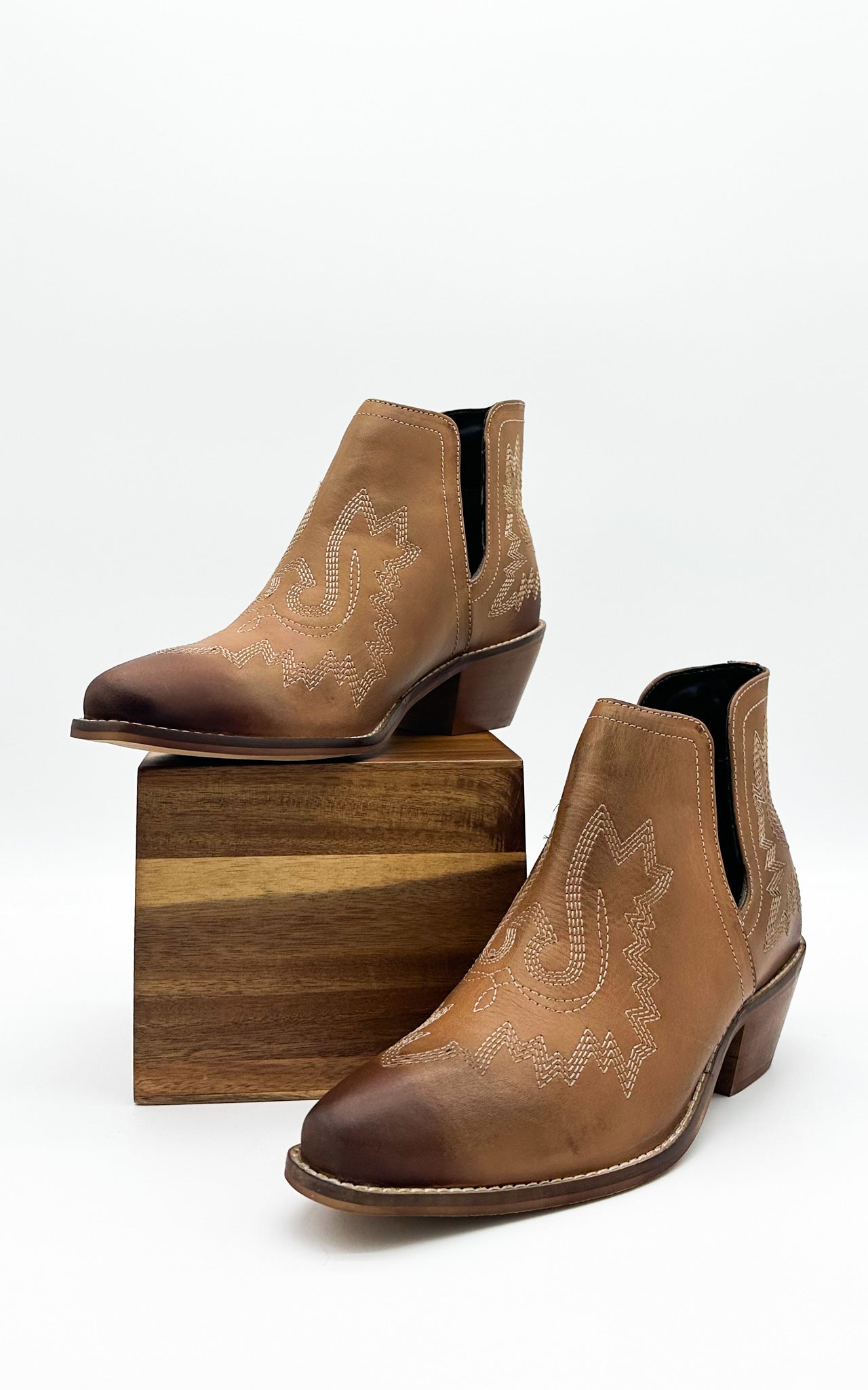 Tan leather booties with Western embroidery, roomy snip toe, cushioned footbed, and ankle slits.