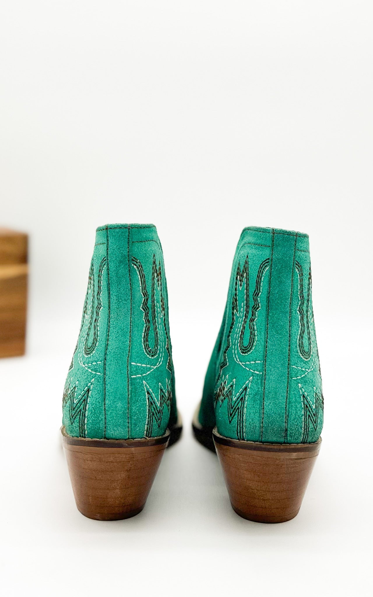 Turquoise leather booties with Western embroidery, roomy snip toe, cushioned footbed, and ankle slits.