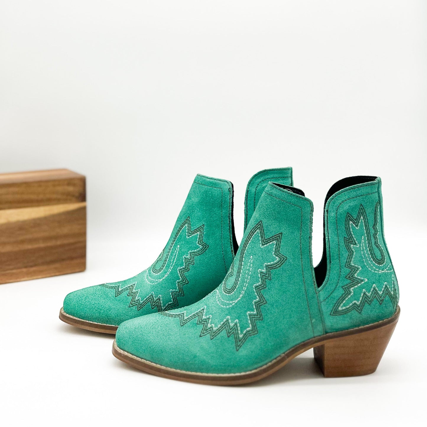 Turquoise leather booties with Western embroidery, roomy snip toe, cushioned footbed, and ankle slits.