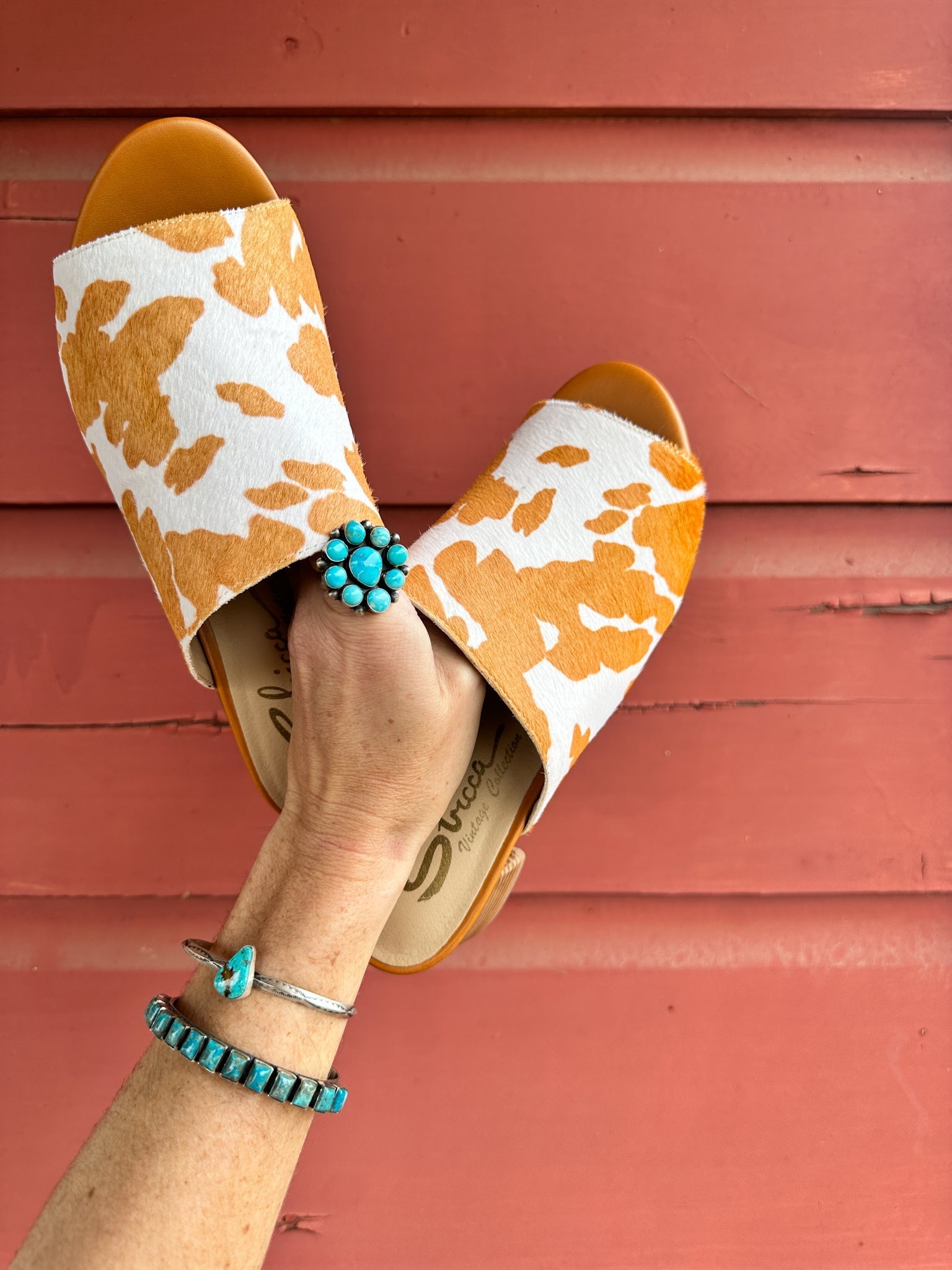 Tan and white cow print mule shoes for women, featuring a genuine calf-hair upper, synthetic lining, padded insole, and internal elastic gore for comfort. Designed with a low stacked leather heel, these slip-on mules are perfect for pairing with jeans, jumpsuits, or other outfits to add a playful, bold touch.