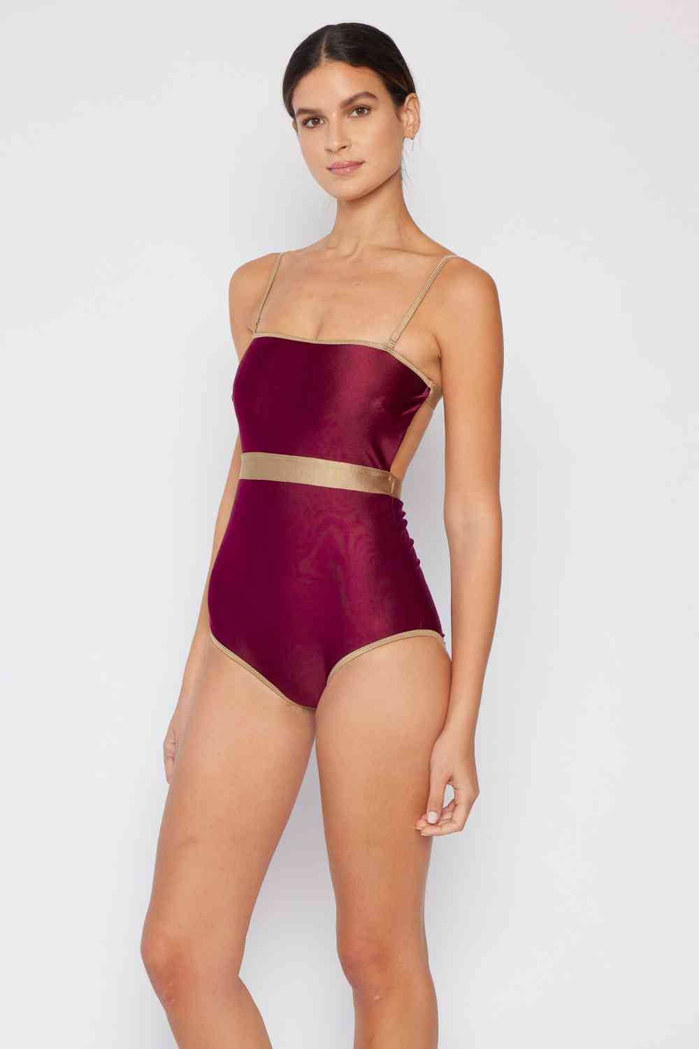 Wine-colored one-piece swimsuit with a contrast waistband, open back, shiny fabric, and a straight neckline.