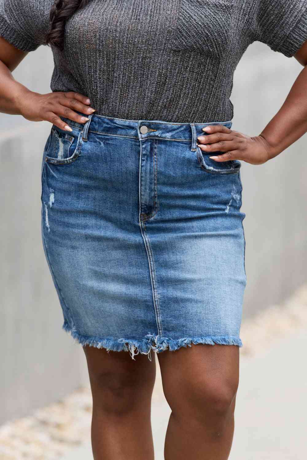 High-rise denim mini skirt with minimal distressing and a raw hem in medium wash.