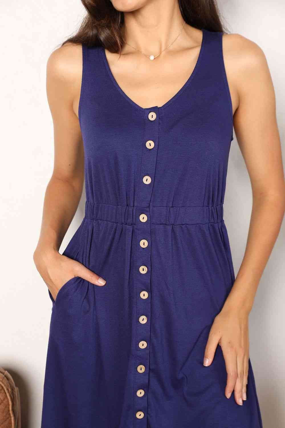 Navy sleeveless dress with a button front, empire waist, and pockets