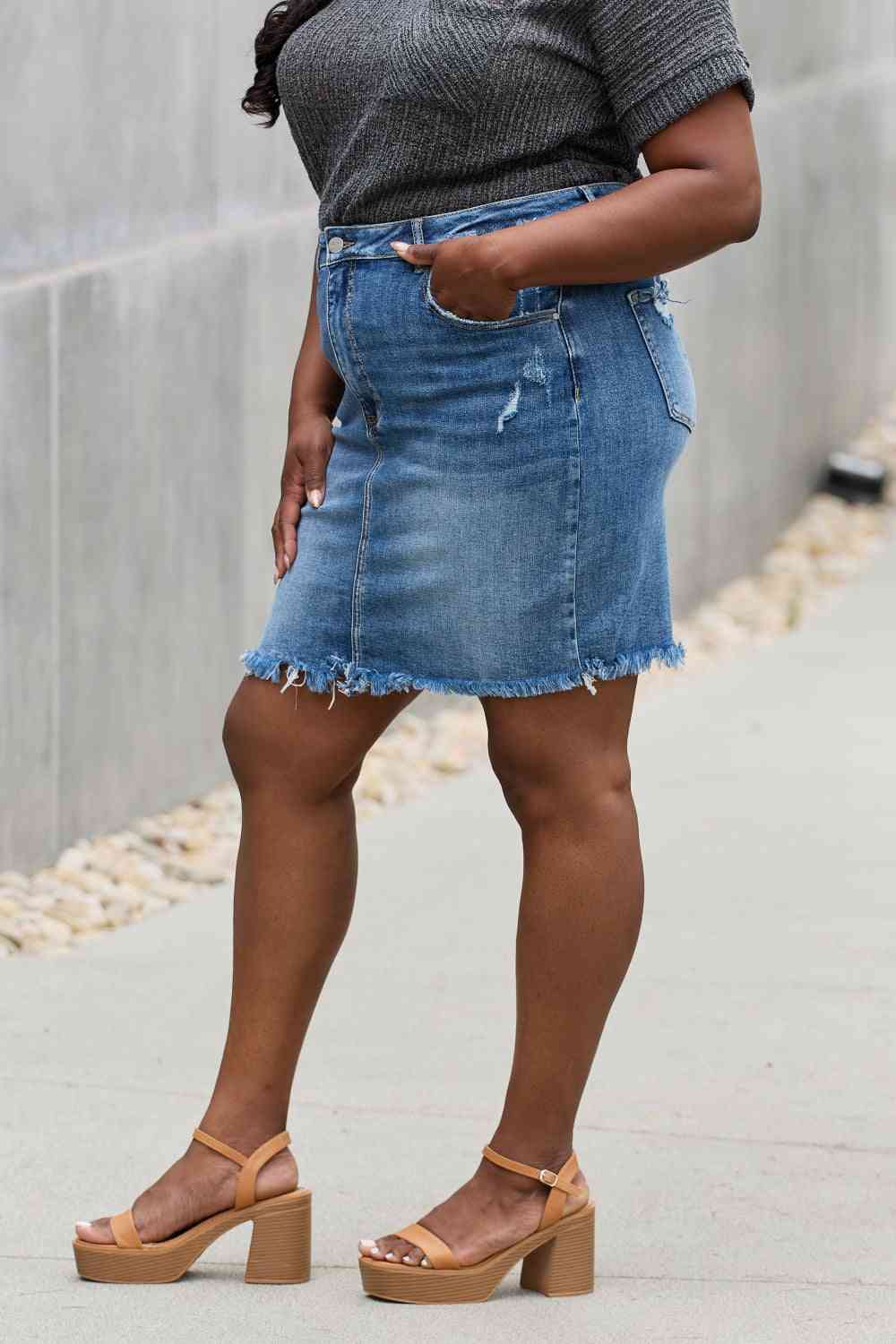 High-rise denim mini skirt with minimal distressing and a raw hem in medium wash.