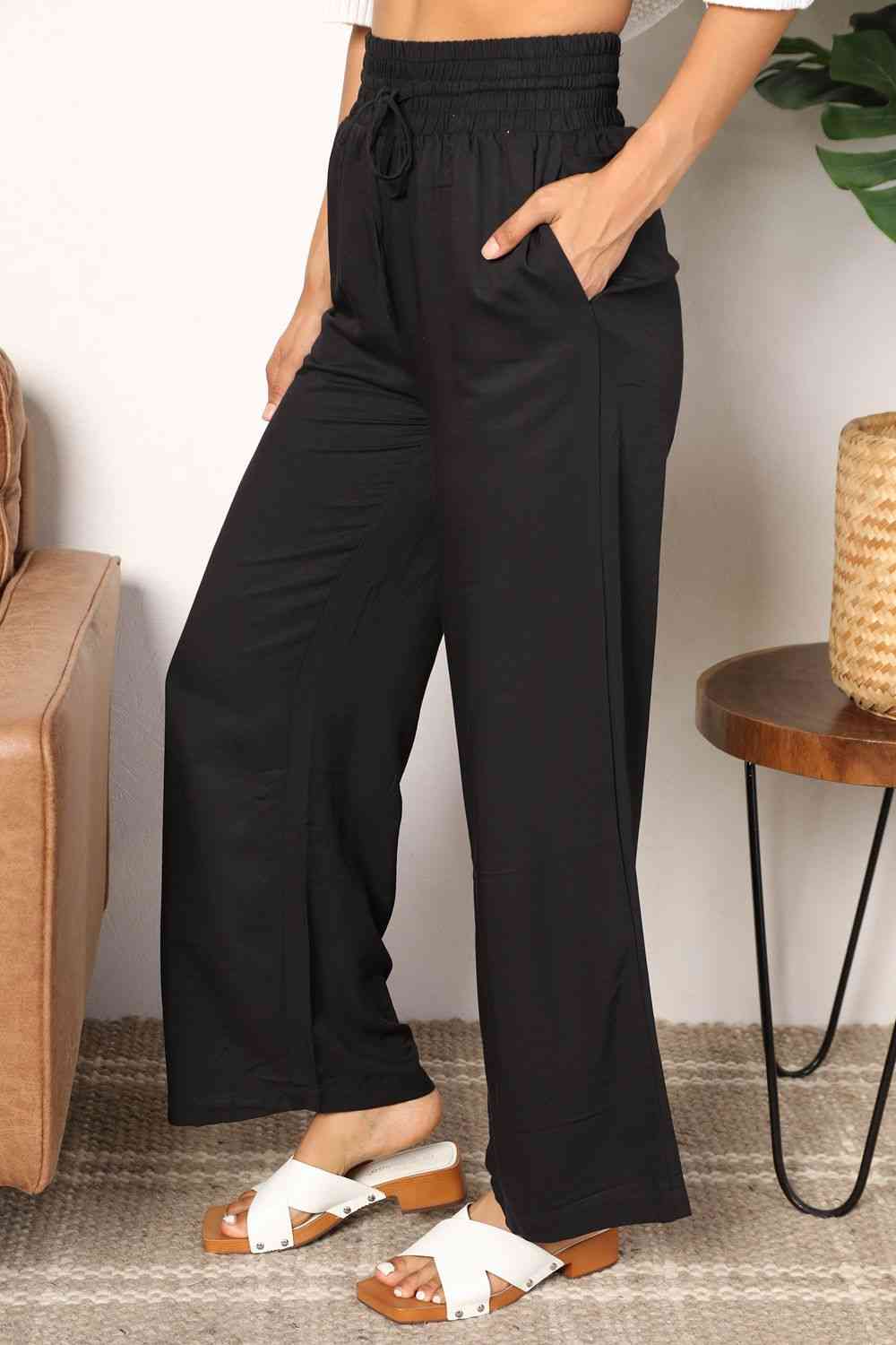 Black wide-leg pants with a drawstring-smocked waist.