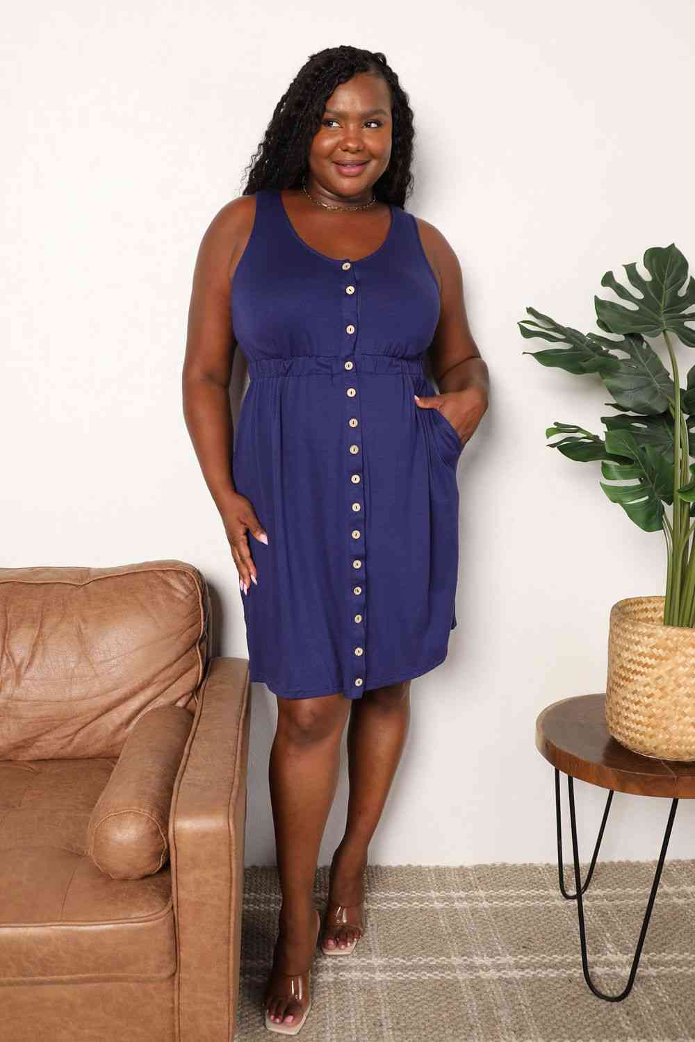 Navy sleeveless dress with a button front, empire waist, and pockets.