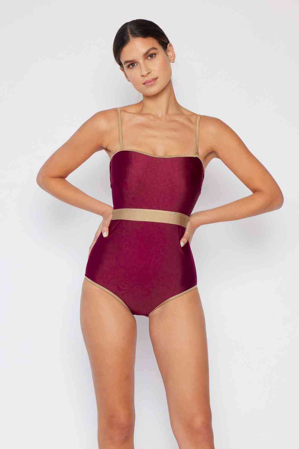 Wine-colored one-piece swimsuit with a contrast waistband, open back, shiny fabric, and a straight neckline.