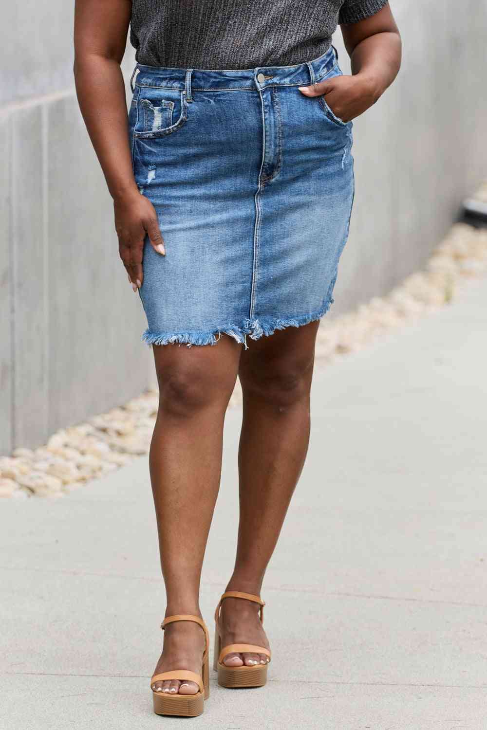 High-rise denim mini skirt with minimal distressing and a raw hem in medium wash.